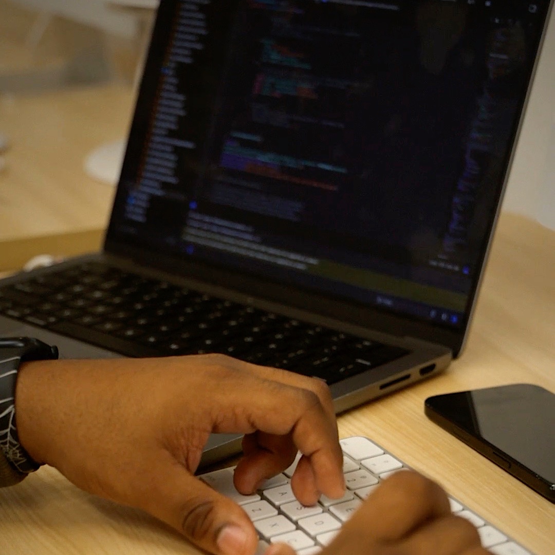 Juan's hands typing on a laptop full of code.