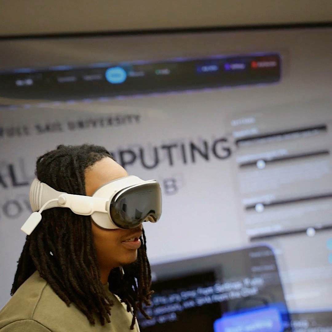 Juan wearing Apple Vision Pro in front of the Spatial Computing Innovation Lab sign.