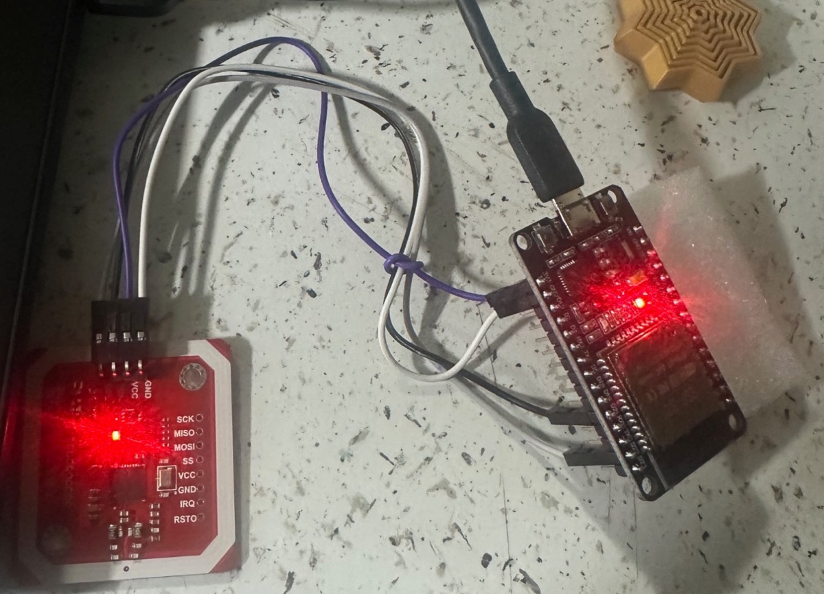 Juan's TouchPoint prototype: a red PN532 NFC reader wired to an ESP32 board, both with glowing LEDs.